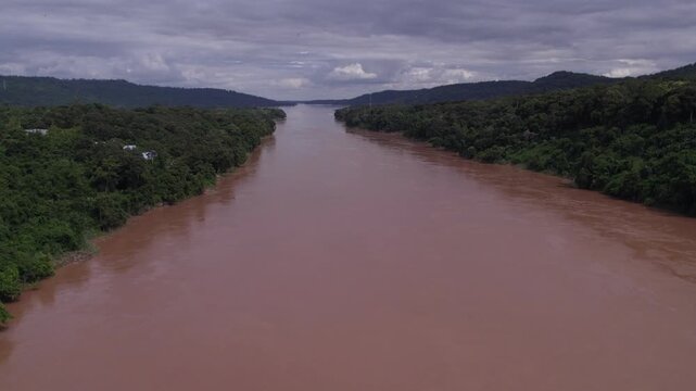 High elevated fest forward moving view of the mekong River during the rainy monsoon season, with cloudy sky in the background.