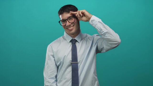 Young hispanic man in shirt and tie salutes with finger to head in bright studio; greeting respect.
