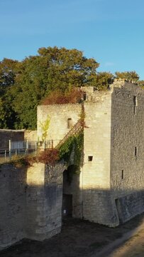 Old stone fortress wall partially covered with ivy, bathed in warm sunlight in La Charite sur Loire, France. Historic architecture with a rustic, medieval atmosphere.