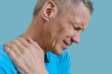 Portrait of adult man with office syndrome backache suffering from muscles pain. Man grimaces in pain, clutching shoulder muscle with sign of myofascial syndrome