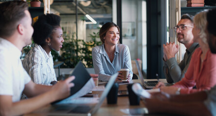 Woman, planning and team at startup for meeting in discussion, documents and happy with laptop at...