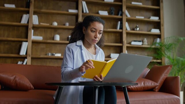 Student checking notes while working on laptop