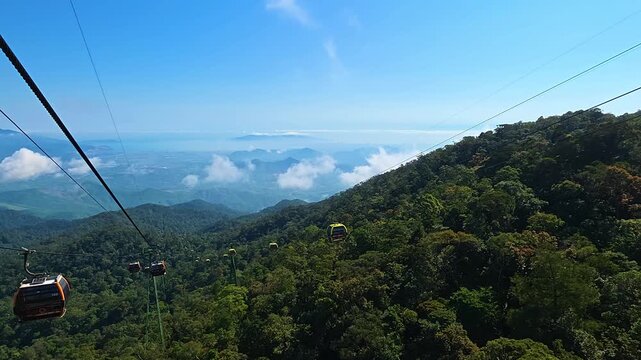 Breathtaking high altitude POV from Ba Na Hills cable car ascending Chua Mountain with sea of clouds, rolling jungle hills and South China Sea beyond
