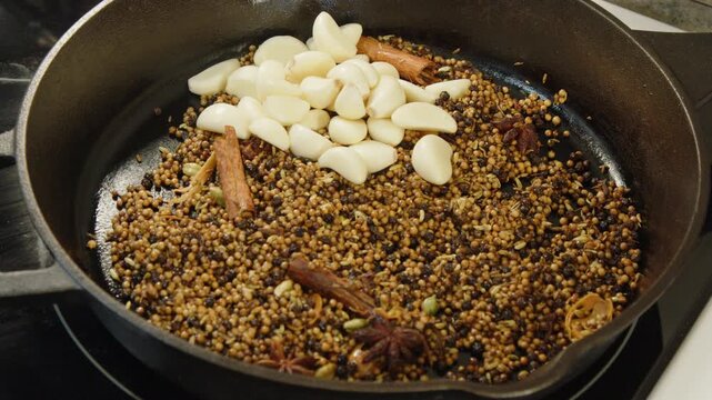 Garlic, hot chili, lichen, bay leaves added to toasted spices in pan