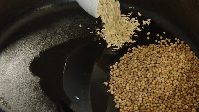 Close-up: Whole aromatic spices are toasted in hot cast iron fry pan