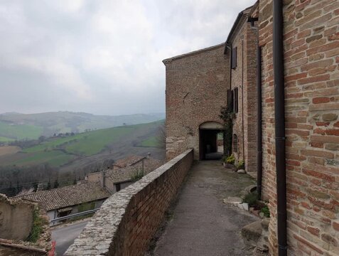 Camminamento sulle mura medievali con vista sulle colline con edifici storici in pietra