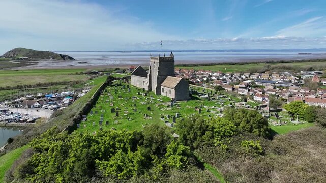 Aerial drone view of Uphill village marina quarry lake and St Nicholas Church hilltop Somerset England