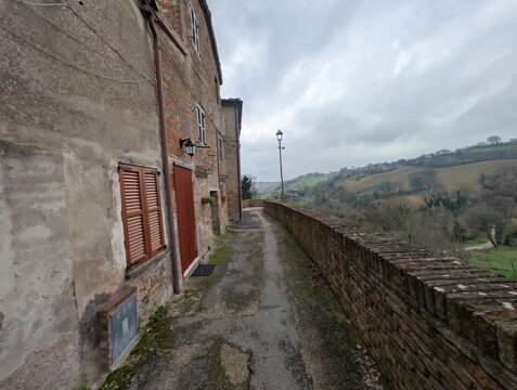 Camminamento sulle mura medievali con vista sulle colline con edifici storici in pietra