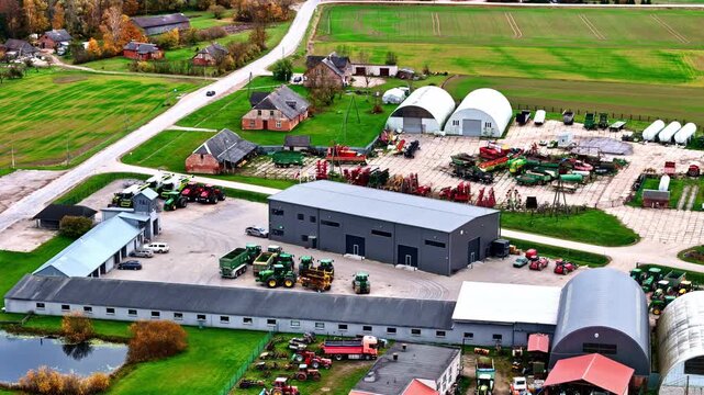 Slow aerial orbit over agricultural machinery dealer yard with tractors and equipment near farmland in Jelgava Latvia autumn