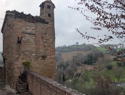 Torre in mattoni su collina con vista rurale e atmosfera tranquilla sotto cielo nuvoloso