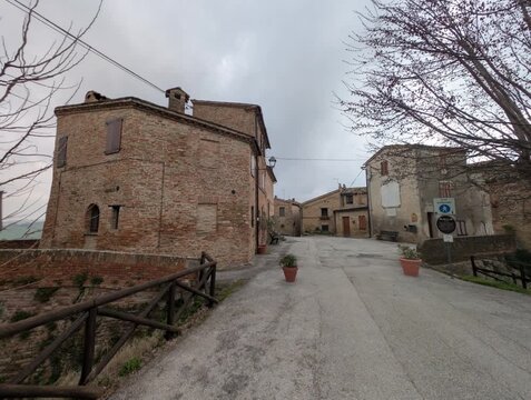 Vicolo storico in salita con edifici in mattoni e atmosfera tranquilla di un borgo italiano