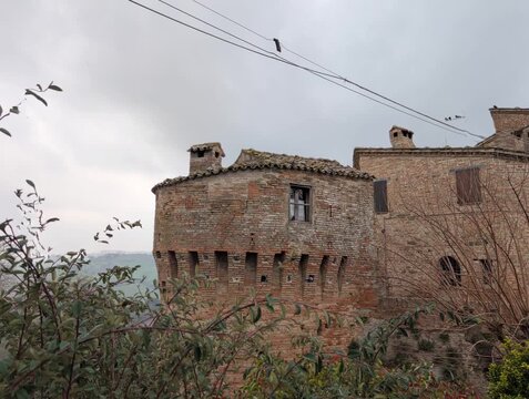 Edificio storico in mattoni con torre cilindrica e atmosfera medievale sotto cielo nuvoloso