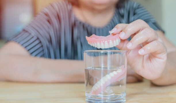 Asian senior or elderly old woman patient holding her partial denture of replacement teeth