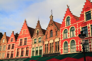 Obraz premium Historic red brick buildings with stepped gables overlook vibrant outdoor cafes, Bruges