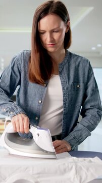 Woman Using Iron To Transfer Custom Design Onto T-Shirt