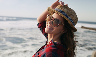 Happy, tourist and woman with shades, beach and relax on summer holiday, travel and break in nature. Ocean, fresh air and person with hat, adventure and traveler with smile on weekend or outdoor