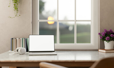 Fototapeta premium White screen laptop and headphones with books and flower pot on marble table and scenery over window