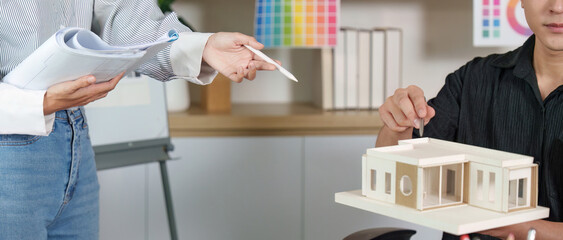 Architect presenting design model to colleague in modern office