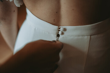 Fototapeta premium Détail des préparatifs de la mariée, main fermant la robe de cérémonie 