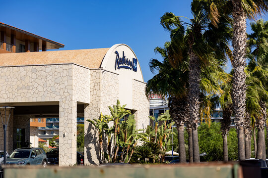 CESME, TURKEY - SEPTEMBER 20, 2025: The exterior facade of the Radisson Blu Resort & Spa in Cesme, featuring the hotel logo and tall palm trees under a clear blue sky