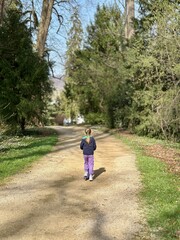 A blonde girl rides a scooter in a spring park.