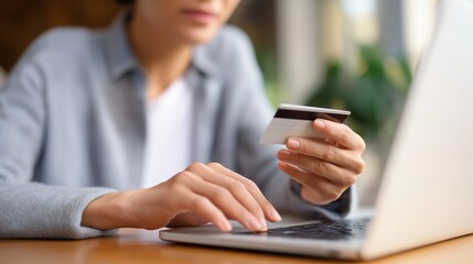 Fototapeta premium Young woman shopping online while holding credit card at home 