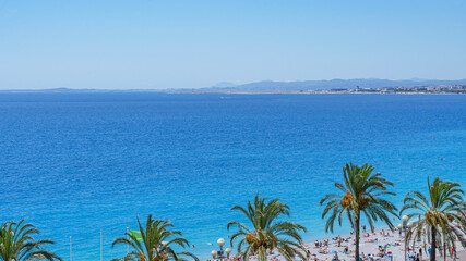 Nice beach with palm trees and turquoise Mediterranean sea on the French Riviera.