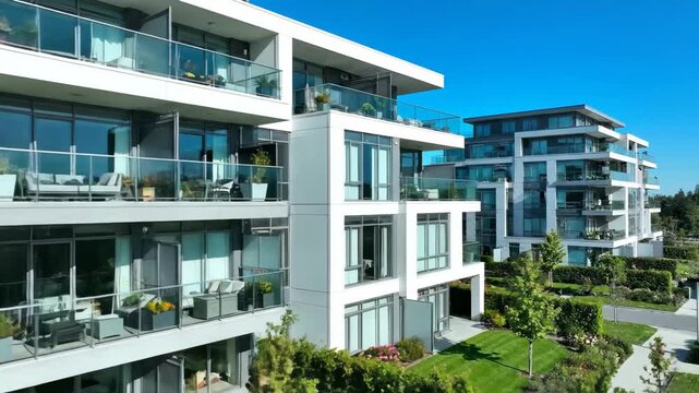 Modern apartment complex with glass balconies and landscaped gardens. Exterior view of a new residential building for real estate and urban development concepts