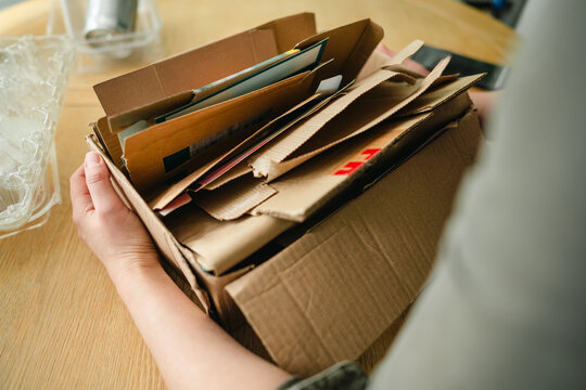 Person holding box of cardboard for recycling and waste sorting indoors
