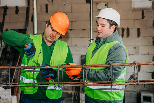 Father and son working together twisting reinforcement at construction site