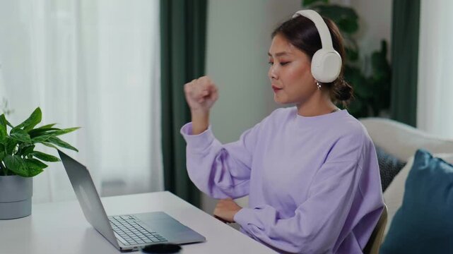 Happy Asian Woman Clicking Send Button and Raising Arms in Success at Home