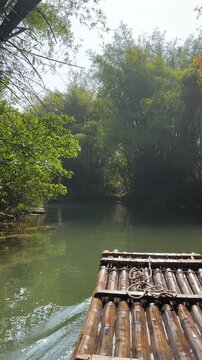 A serene bamboo rafting journey through a lush river landscape, showcasing beautiful natural views, a quintessential travel experience reminiscent of Foshan and Guilin in China