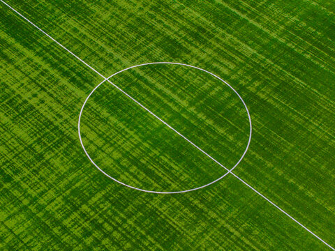 Aerial view of a vibrant green football field with crisp white lines forming a perfect circle against the textured grass, Warsaw, Masovian Voivodeship, Poland.