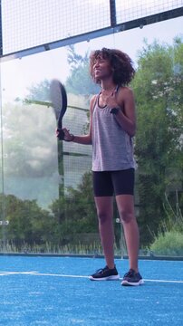 Vertical video: Swinging woman in sportswear bending forward, practicing paddle shots on blue court