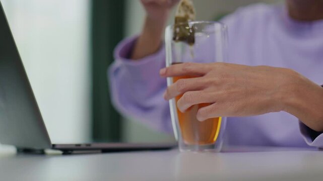 Close-up of Hands Dipping Tea Bag into Hot Water