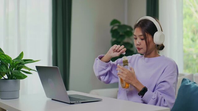 Asian Woman Brewing Hot Tea at Her Home Office Desk for a Relaxing Break