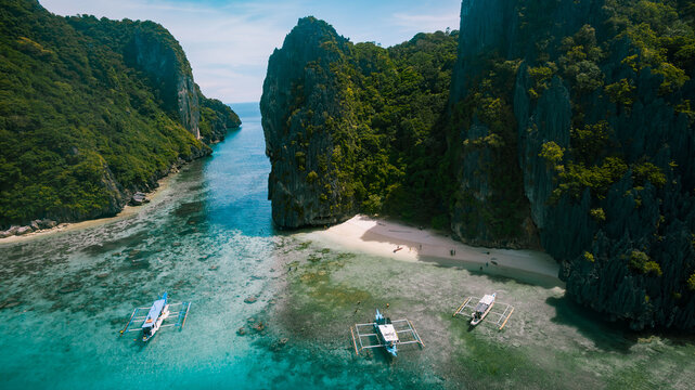 Aerial view of turquoise waters meet the striking limestone cliffs of Helicopter Island, a tropical haven, El Nido, Mimaropa, Philippines.