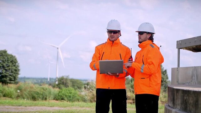 Industry professionals discuss renewable energy solutions at wind farm outdoor setting informative meeting collaboration