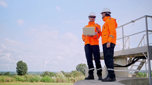 Workers analyzing data on laptop wind farm action shot outdoor environment close-up view renewable energy concept