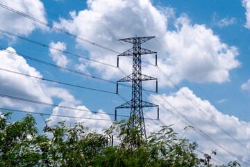A striking photo of a power pylon against a vibrant blue sky with fluffy clouds. This image...