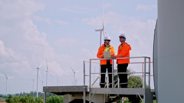 Wind energy inspection renewable energy site professional collaboration outdoor environment two engineers overseeing turbines