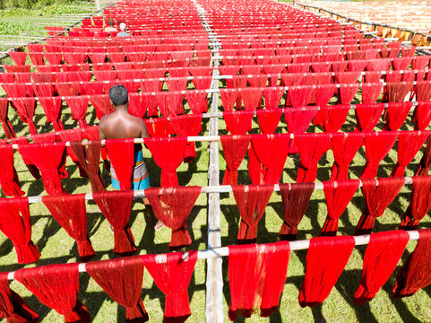 Aerial view of vibrant red dyed threads hanging to dry in rows, creating a striking pattern of color and texture, Narayanganj, Dhaka Division, Bangladesh.