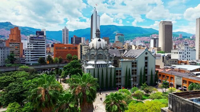 Drone shot of Medellin Metro near Botero Plaza in Medellin, Colombia, capturing urban transit, city architecture, and the movement of trains through the downtown landscape.