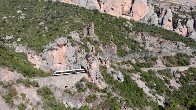 Aerial, drone following a train among a rugged terrain in Catalonia