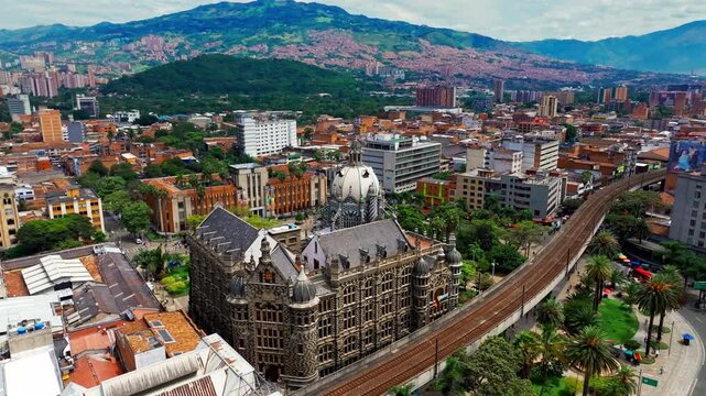 Drone shot of Medellin Metro near Botero Plaza in Medellin, Colombia, capturing urban transit, city architecture, and the movement of trains through the downtown landscape.