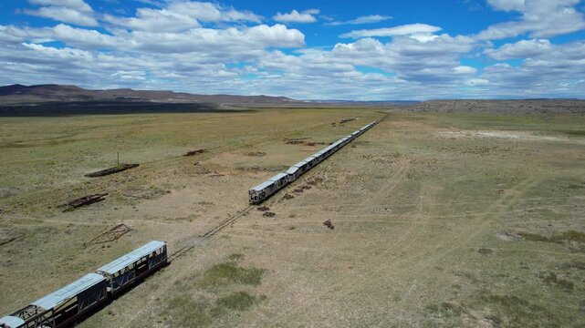 Aerial diagonal shot over old train roofs revealing wheels and telegraph lines