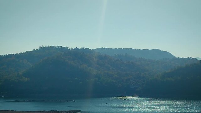 Narmada River landscape near Kevadia, Gujarat, India. Shimmering river water with green forest hills and clear sky. Scenic natural environment in western India near Statue of Unity tourism region.