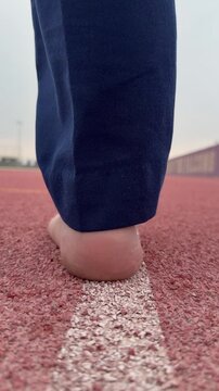 A man walks along the NYUAD rubber track, following a straight, simple line that feels symbolic and quietly purposeful.