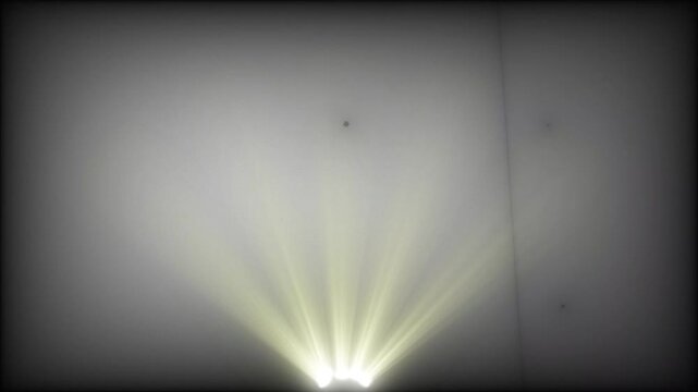 A video showcasing a bright light shining through a dark room with a gray wall