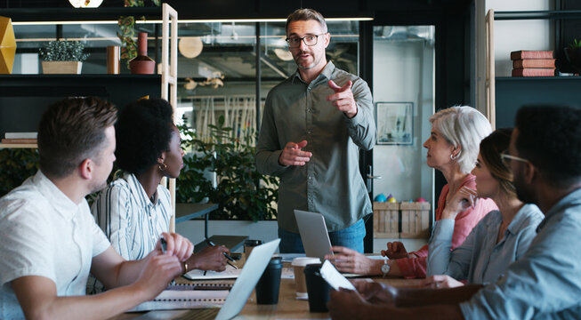 Business, team and man with meeting in office for editorial guidance, writing advice or feedback. Journalists, lead editor and discussion with pointing for topic delegation, story ideas or planning